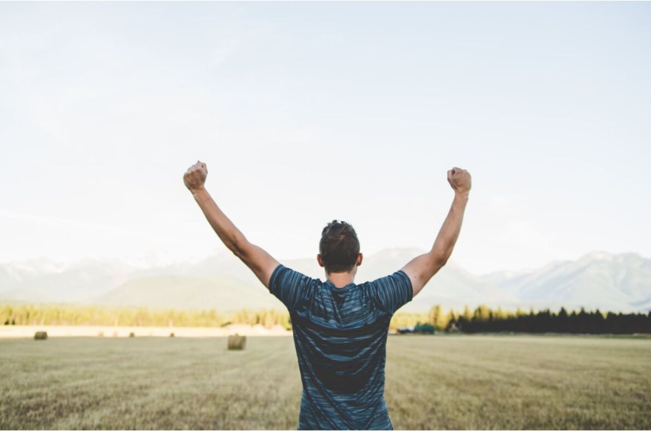 Person in a field raising arms as a sign of victory